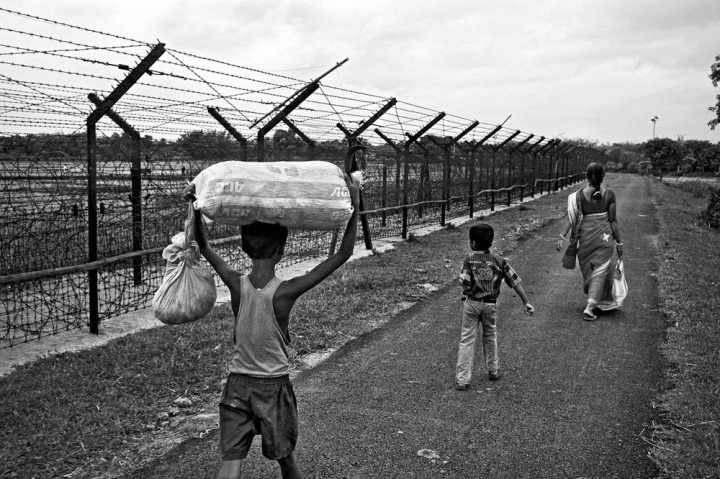  Inde, Province du Bengale-Occidental, 30 mai 2013 Dans la région de Balurghat, une mère et ses deux enfants vont rendre visite à des membres de leur famille habitant dans un village voisin, à proximité de la clôture. © Gael Turine / Agence VU