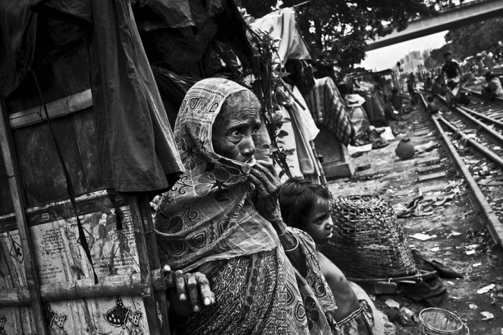 Bangladesh, Dacca, 02 septembre 2012 - Jotana, 65 ans, est arrivée à Dacca une semaine auparavant. Elle a rejoint son fils qui vit dans un quartier pauvre depuis trente ans. Elle vient de la région frontalière de Sathkira mais elle ne pouvait pas subvenir seule à ses besoins dans son village d'origine. Ses deux autres fils sont contrebandiers et elle ne les voit plus car ils doivent se cacher des gardes-frontières du Bangladesh. Le quartier est dangereux à cause des trains qui passent près des maisons. Les accidents impliquant les enfants et les personnes âgées sont assez fréquents. © Gael Turine / Agence VU