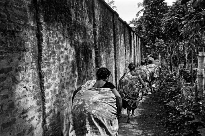 India, West Bengal Province, Hili 29 May 2013 The border town of Hili is highly guarded by the Indian Border security Force (BSF) because it's an official point of passage for the trucks. Bangladeshi women carrying bags full of goods, are walking along the border wall that runs along the city. They just bought Indian goods (spices, jewels, make-up...) that they will sell in Bangladesh. They prefer to travel as a group in order to escape easier if a BSF soldier is coming. Inde, Province du Bengale-Occidental, Hili, 29 mai 2013 A Hili, ville frontalière dotée d'un point de passage officiel pour les camions de marchandises et donc hautement surveillée par la Indian Border security Force (BSF). Un groupe de Bangladaises, passé illégalement en Inde, courent au pied du mur-frontière érigé tout le long de la ville. Elles ont acheté des marchandises indiennes (épices, bijoux, produits de beauté, médicaments,...) qu'elles revendront au Bangladesh. Elles préfèrent effectuer ce type de passage en groupe de manière à pouvoir s'éparpiller et s'échapper plus facilement si un soldat de la BSF intervient. Gael Turine / Agence VU