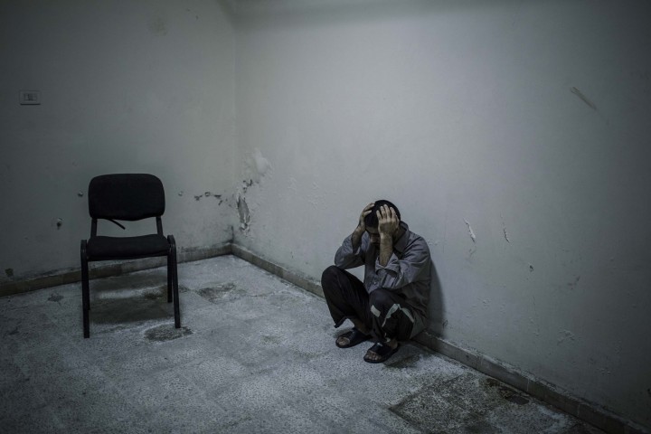 Said Ahmed Hussein (23 ans), prisonnier afghan, reste muré dans le silence dans la prison de Jibha al-Shamiya située à l'est d'Alep. Il a été fait prisonnier par l'Armée Syrienne Libre en octobre 2014 à Almallah, au nord d'Alep. Alep - SYRIE 03/05/2015 Quand je suis arrivé dans leur cellule, j'ai vraiment été marqué par leurs regards infiniment tristes. Ils avaient les yeux plongés dans le vide et ne bougeaient pas. Une odeur tenace d'humidité régnait dans la pièce. On les avait habillé avec de nouvelles chemises, comme s'il fallait qu'il soient présentables pour l'interview ou pour montrer qu'ils étaient bien traités. Ils nageaient dans ces chemises, bien trop grandes pour eux. Cette photo a été prise après l'interview. Je suis resté 1h ou 2 avec eux, dans le silence le plus complet. Ils ne m'adressaient la parole que pour me demander des cigarettes. Ils ne s'arrêtaient pas de fumer. Alors je me suis assis et j'ai fumé avec eux, toujours dans le silence. Apres un moment, il fallait que je parte pour prendre des photos a Alep. Apres leur avoir laissé mon paquet de cigarettes, nous nous sommes serrés la main, sans un mot. Et je suis parti.