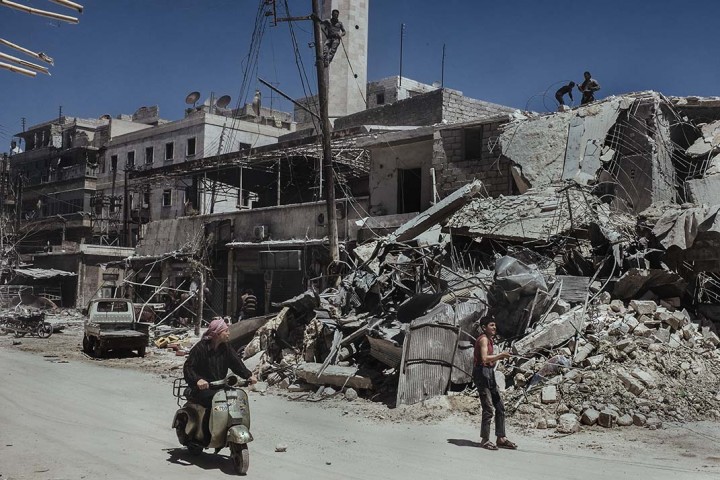 Les passants regardent les dŽcombres de l'Žcole dŽtruite par une bombe baril (larguŽe par les forces gouvernementales) dans le quartier de Saif Al-deawla, au sud ouest d'Alep, SYRIE 03/05/2015