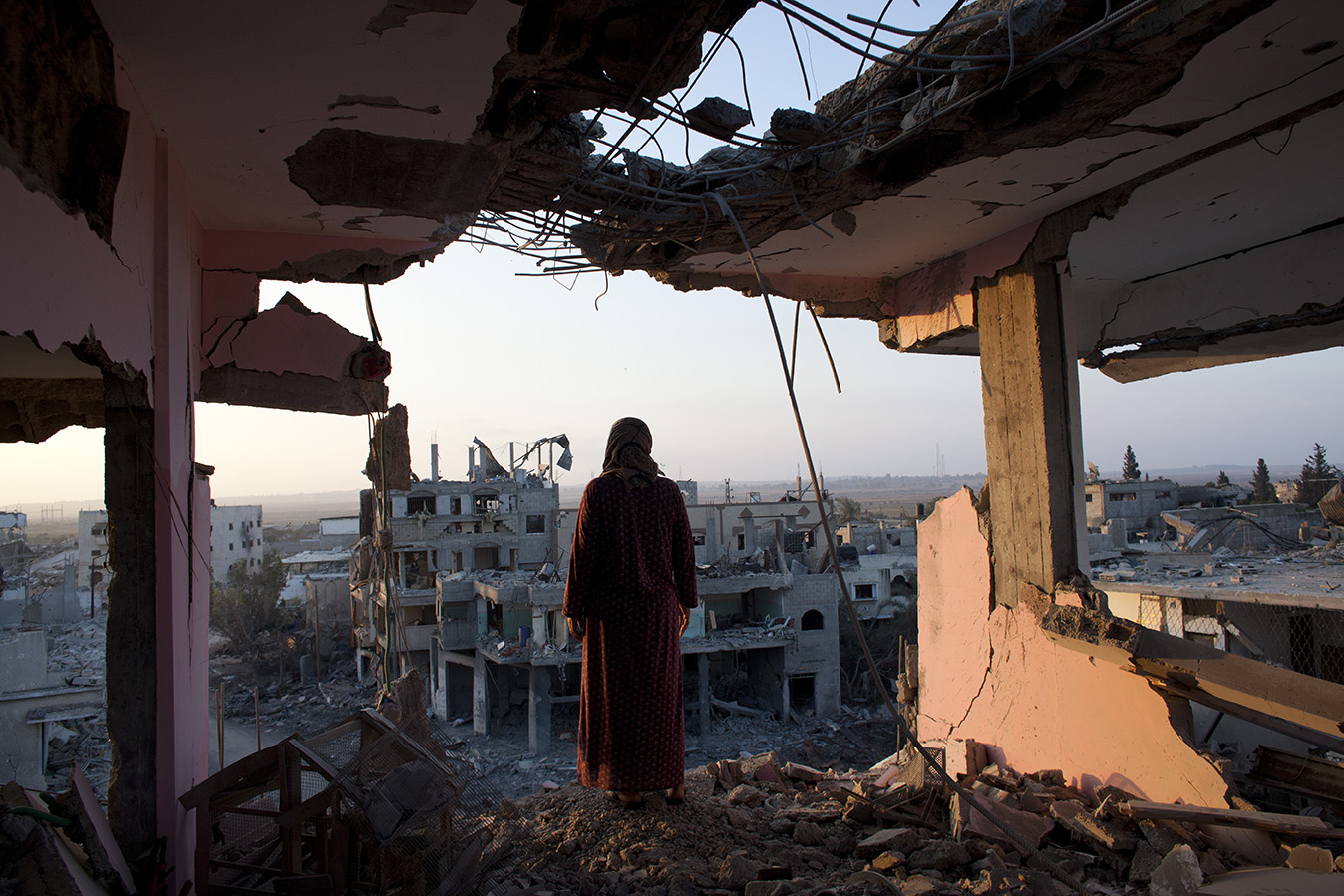 Hidya Atash, palestinienne, observe peu après l’aube les décombres du quartier Shujayea depuis le dernier étage de sa maison familiale détruite par des tirs israéliens. Elle et sa famille de 40 membres ayant fui les attaques de l’armée de l’air israélienne, elle n’a pu constater l’étendue des dégâts que lors de son retour, durant un cessez-le feu temporaire.