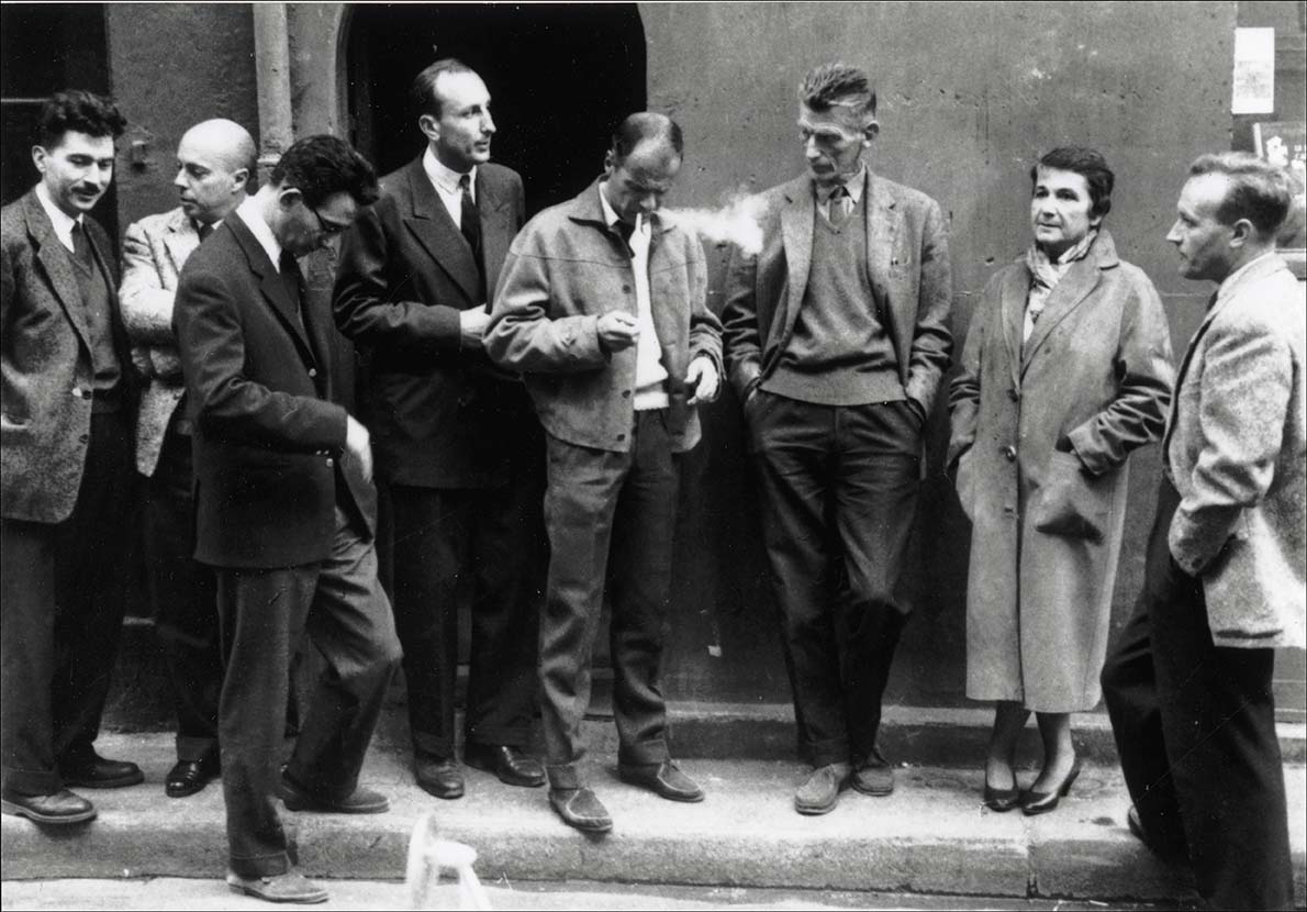 Portrait des ecrivains du Nouveau Roman : de gauche a droite : Alain Robbe-Grillet (Robbe Grillet), Claude Simon, Claude Mauriac, Jerome Lindon, Robert Pinget, Samuel Beckett, Nathalie Sarraute, Claude Ollier devant le siege de la maison d'edition "Les editions de Minuit", 1959. ©Dondero/Ed. Minuit/Leemage