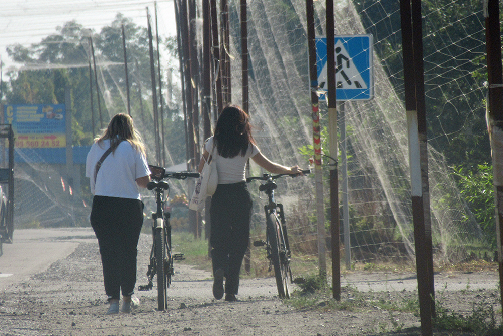 A l'entrée de Kramatorsk le 2 septembre 2026 et afin de passer d'une maison à une autre, ces deux femmes circulent dans le tunnel de filets. Photographie Thierry Birrer.