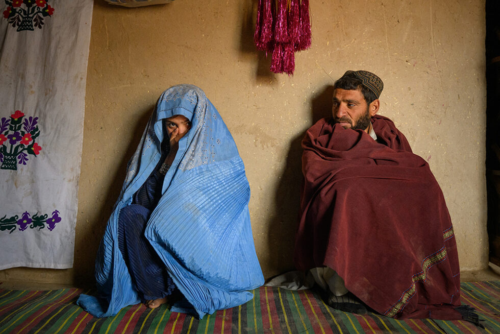 Bulbul (14 ans) assise aux côtés de son père Mansour (35 ans) dans leur maison à Khushkian. Bulbul est enceinte de l’homme de 45 ans auquel son père l’a mariée. Afghanistan, mars 2026. Photographie: Élise Blanchard